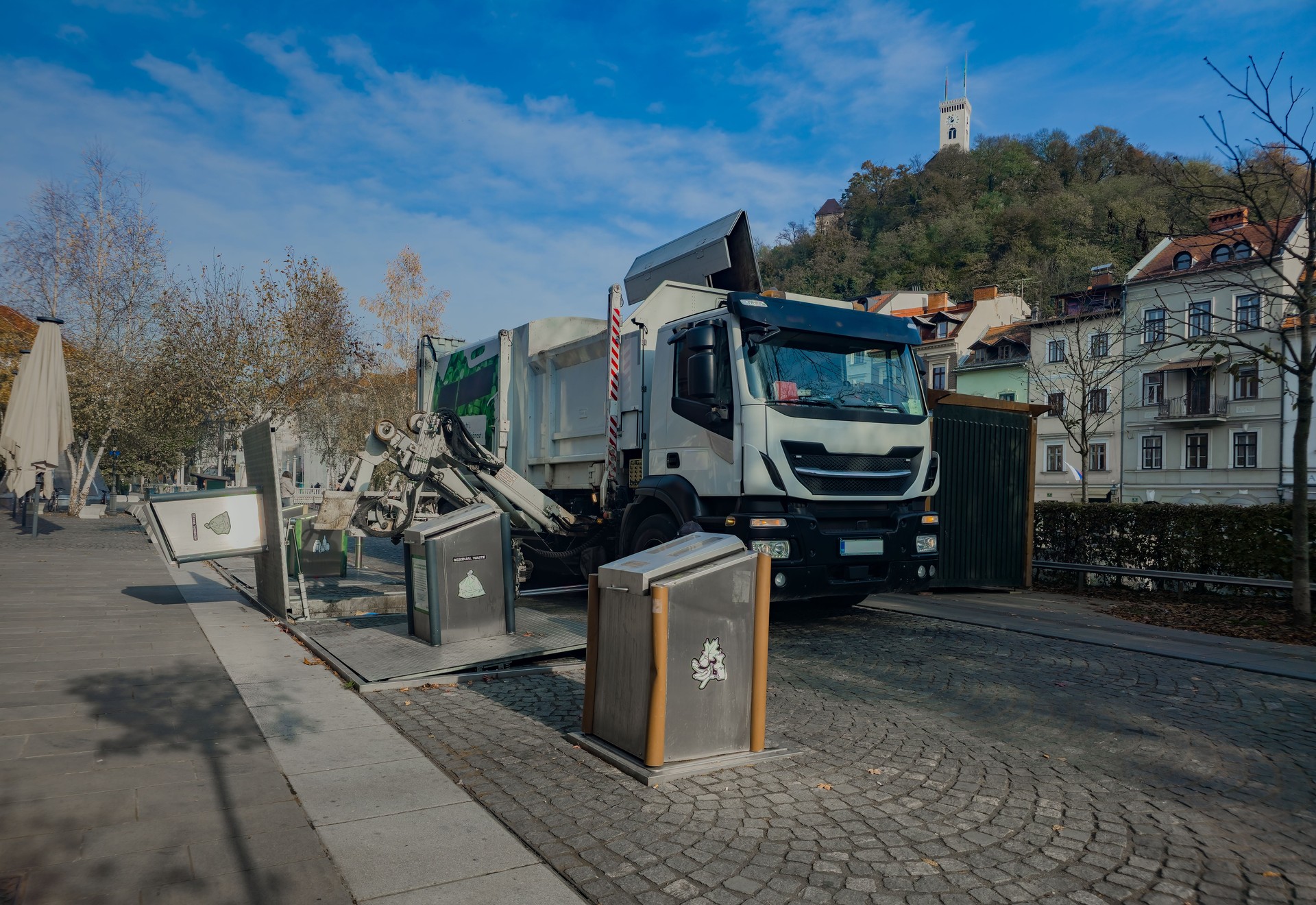 Urban Recycling Truck Emptying Underground Containers on a Sunny Day