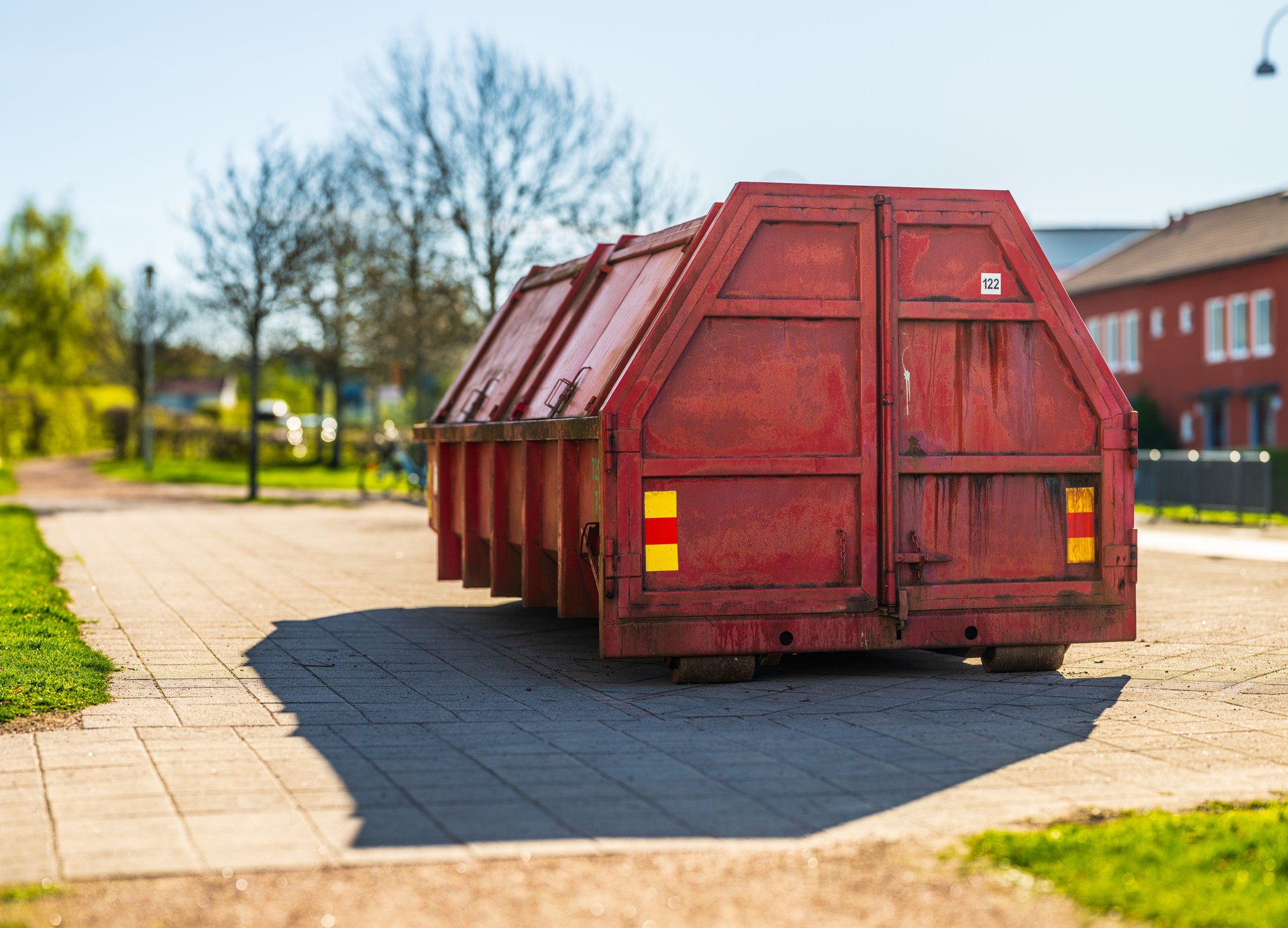Rear view of red dumpster on paved path..