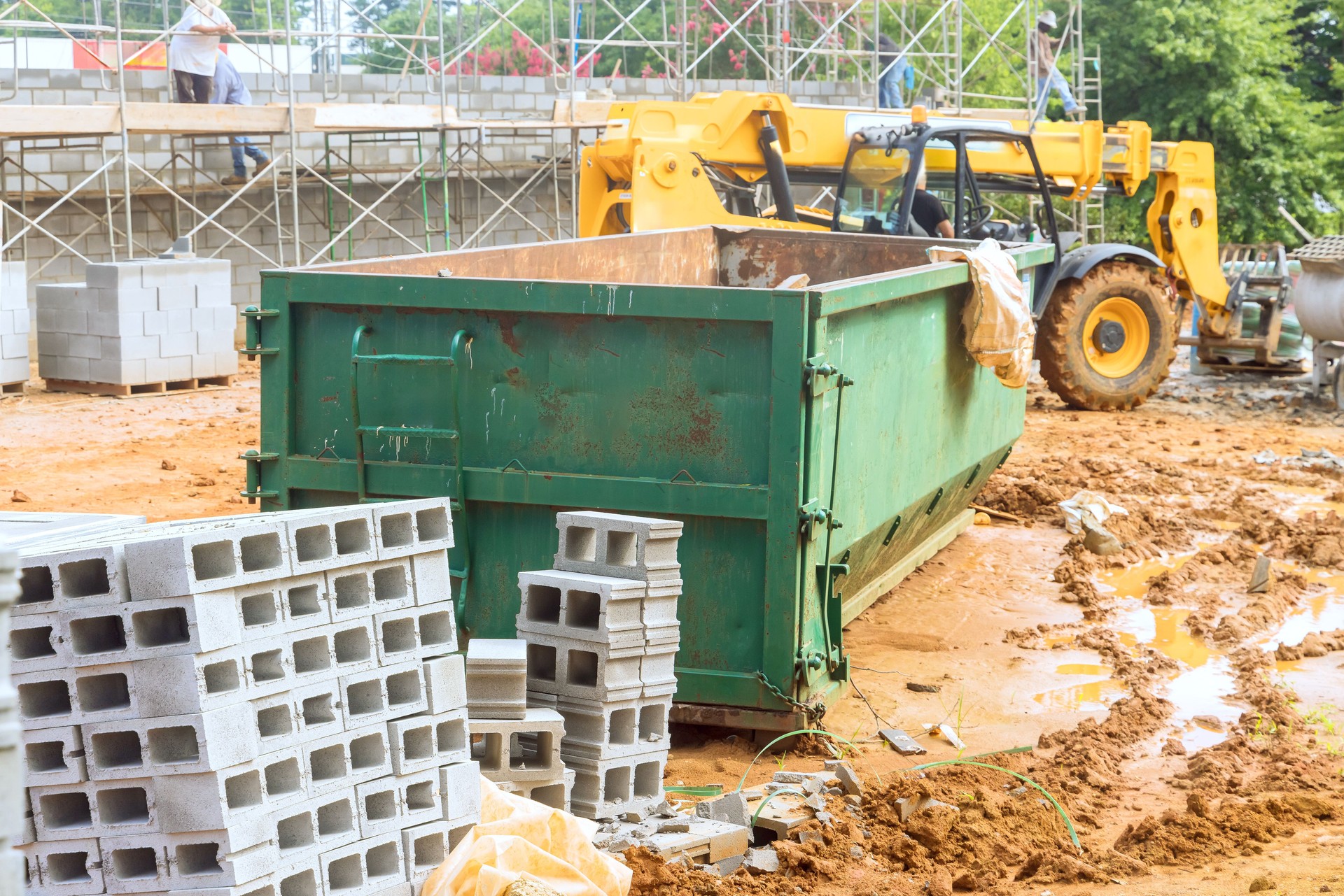 An empty dumpster for construction waste debris near a construction site is loaded up with debris