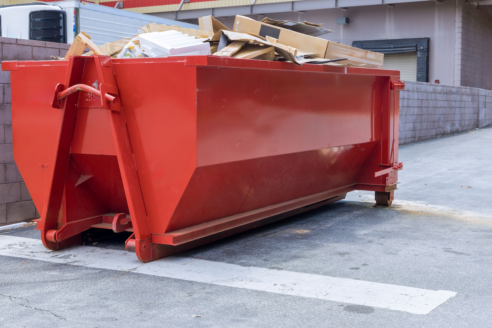 Near construction site, there is a dumpster loaded with construction waste debris